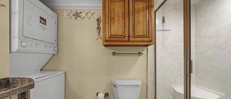A compact bathroom with a toilet, a small sink, and a shower area.