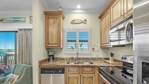 A kitchen with wooden cabinets, a stainless steel dishwasher, a microwave, and a stove. - 1 bed Beach Pools Waterfront Boating Palmaway (Orange Beach)