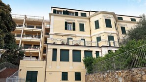 A multi-story building with balconies, a stone wall, and a metal fence. - Holiday Home 'Appartamento A2' with Air Conditioning (Sanremo)