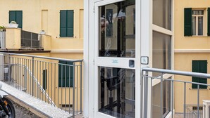 A building with a white door, green shutters, and a metal railing. - Holiday Home 'Appartamento A2' with Air Conditioning (Sanremo)