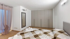 A bedroom with a bed, a wardrobe, a mirror, and a window with curtains. - Holiday Home 'Appartamento A2' with Air Conditioning (Sanremo)