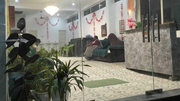 A reception area with a marble counter, potted plants, and a statue. - Shri Dham Hotel And Resort (Ayodhya)