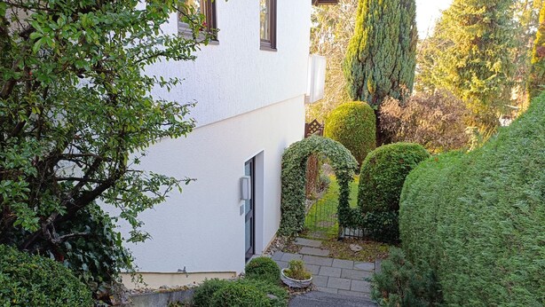 A narrow stone pathway leading to a white building with a door, surrounded by well-maintained hedges and trees. - Vacation apartment Elversberg (Spiesen-Elversberg)