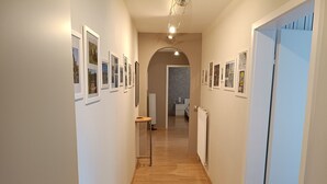 A hallway with framed pictures on the walls, a radiator, and a door on the right. - Vacation apartment Elversberg (Spiesen-Elversberg)