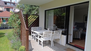 A patio with a table and chairs, a wooden fence, and a view of a house in the background. - Vacation apartment Elversberg (Spiesen-Elversberg)