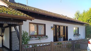 A two-story house with a tiled roof, wooden porch, and a fenced yard. - Vacation apartment Elversberg (Spiesen-Elversberg)