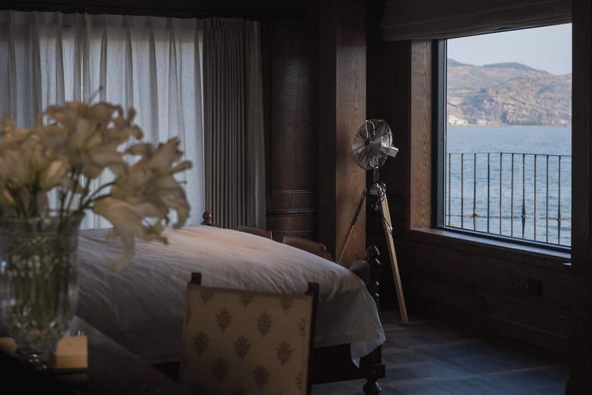 Un dormitorio con cama, una silla, un ventilador y vistas al mar.
