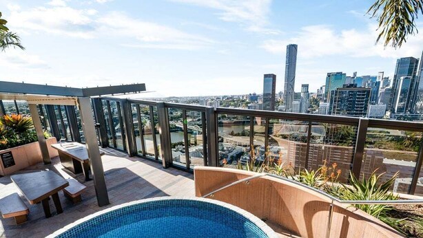 Piscina no terraço com vista para a cidade, área de estar externa e pérgola.