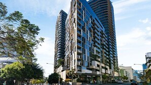 Um edifício moderno e imponente, com vários andares, janelas amplas e um design de canto marcante.