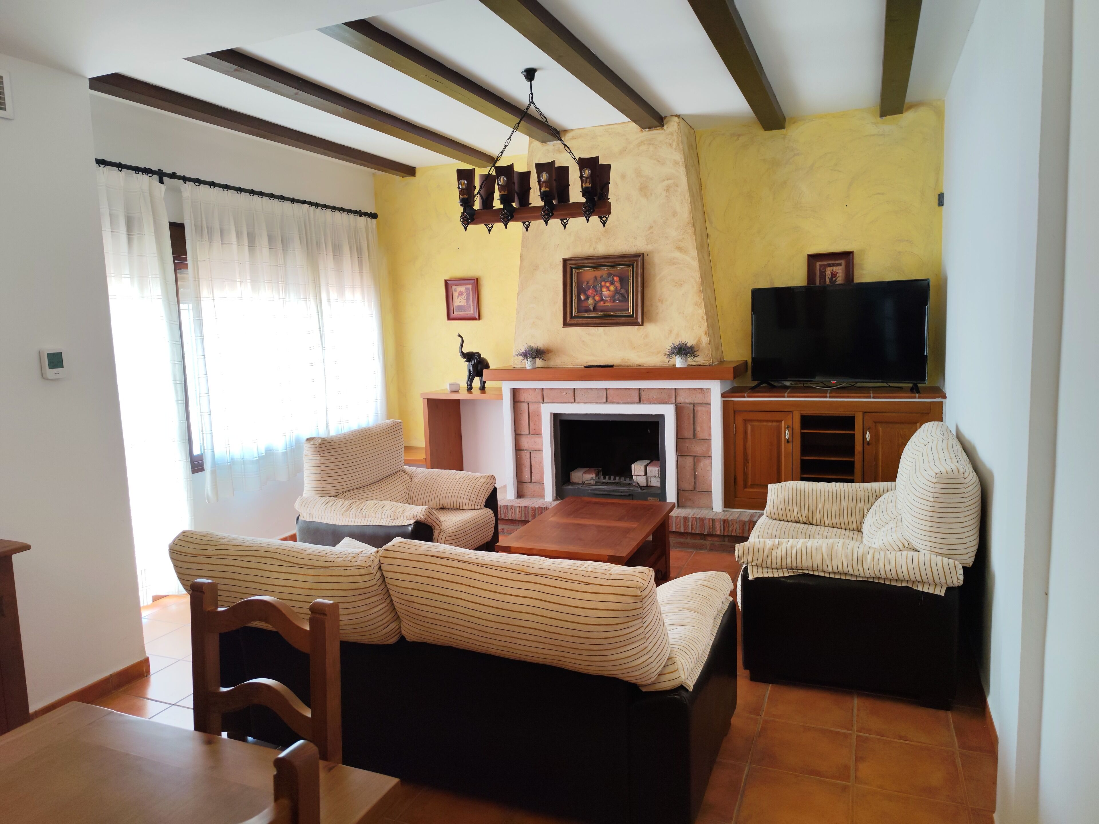 A living room with striped sofas, a wooden coffee table, a fireplace, a television, and a ceiling fan.