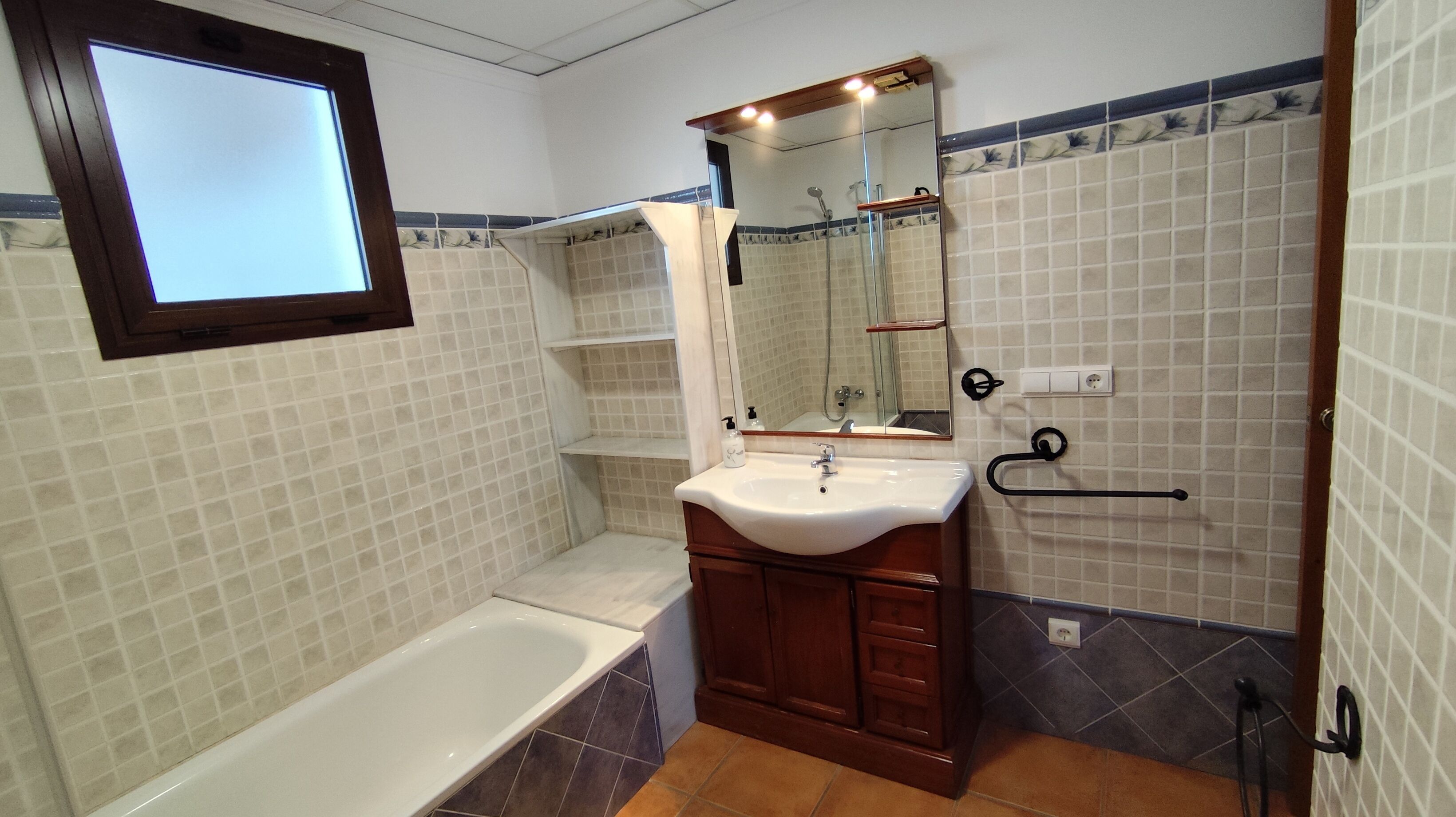 Un baño con bañera, lavabo, espejo y ducha.