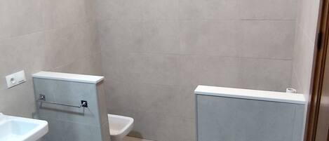 Une salle de bain comprenant des toilettes, un lavabo et un espace douche.
