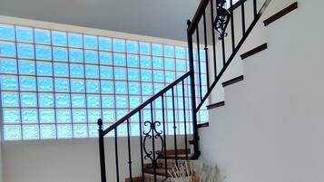 Un escalier avec une rampe noire, une plante en pot et une fenêtre à carreaux.