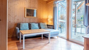 A wooden-paneled room with a sofa, a table, and a window with curtains. - FerienPark Kreischberg Ferienhäuser by ALPS RESORT (Sankt Lorenzen ob Murau)