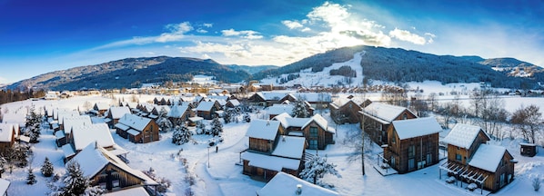 A snow-covered village with wooden cabins and a mountain backdrop. - FerienPark Kreischberg Ferienhäuser by ALPS RESORT (Sankt Lorenzen ob Murau)