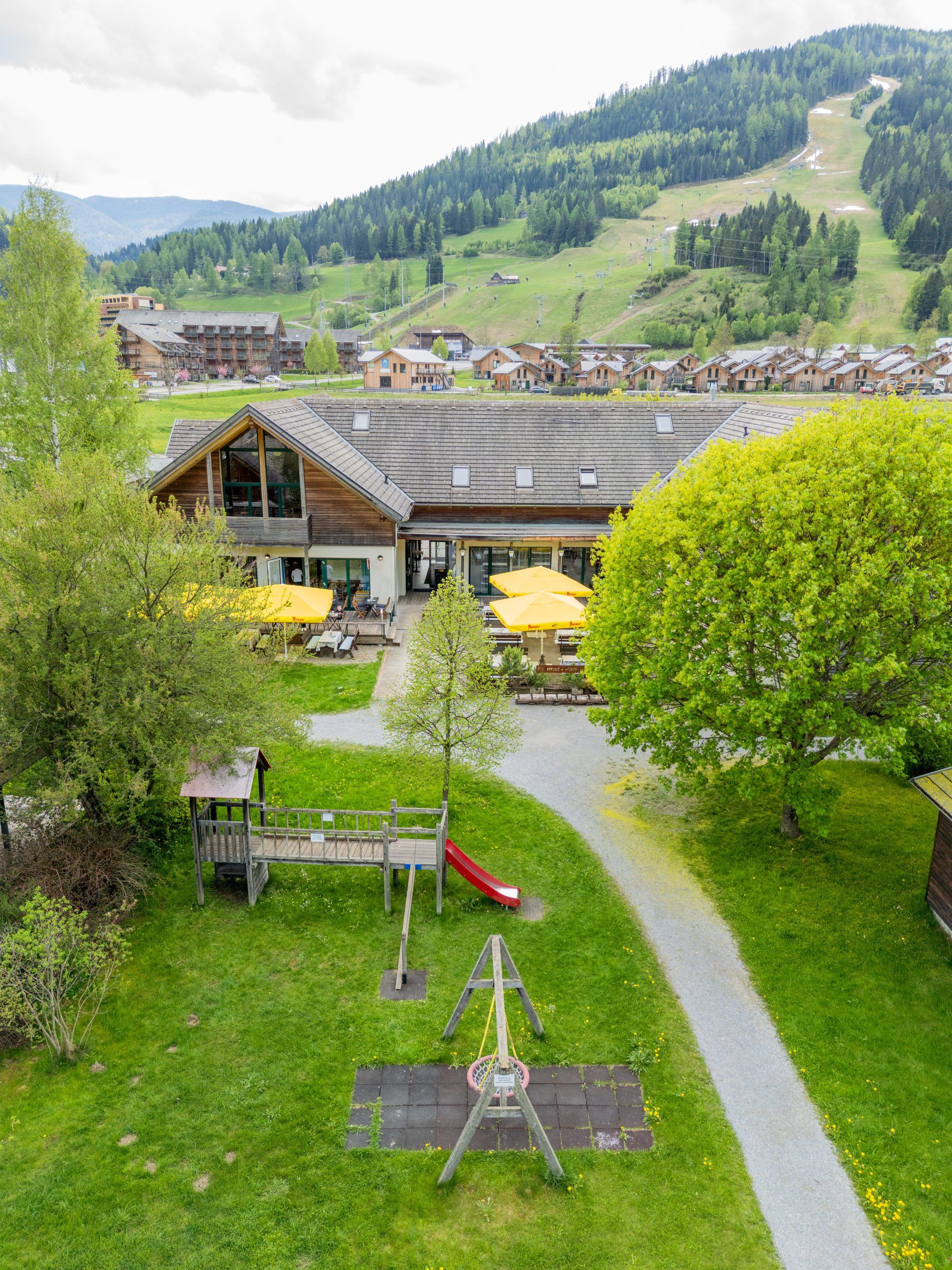 A lodge with a patio area, a playground, and a view of a mountainous landscape.