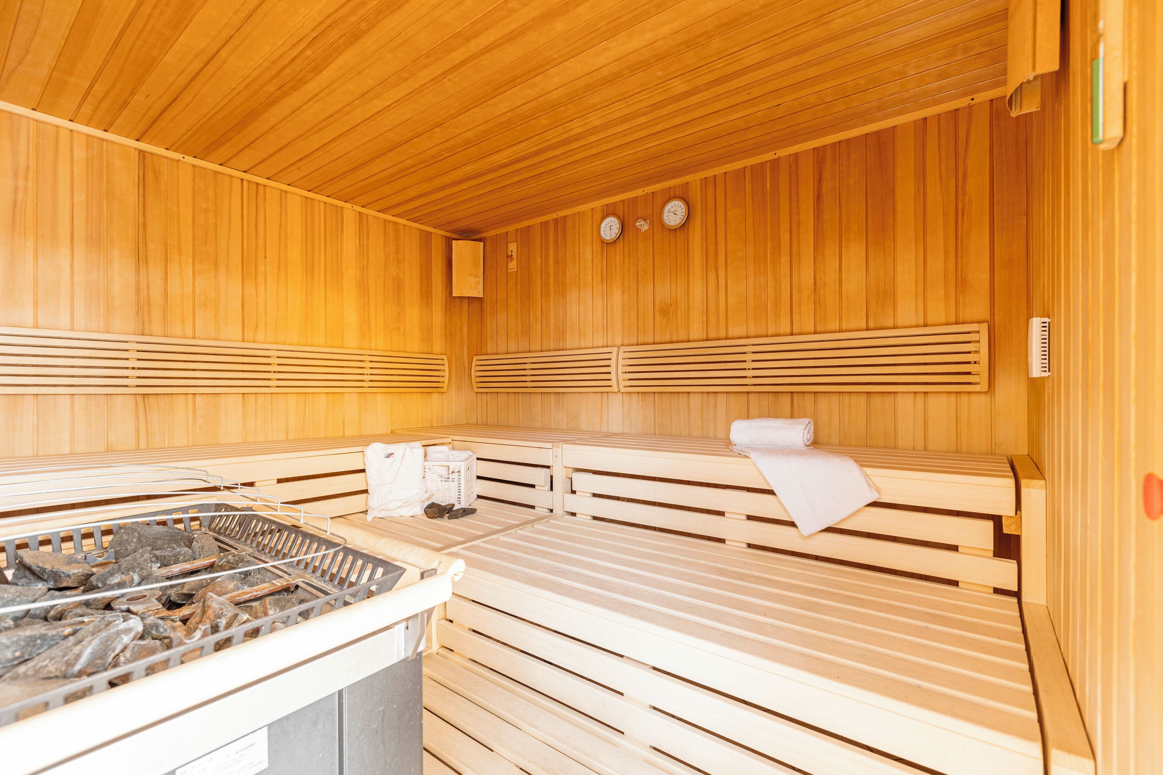 Een sauna met houten banken, een warmtebron en handdoeken.