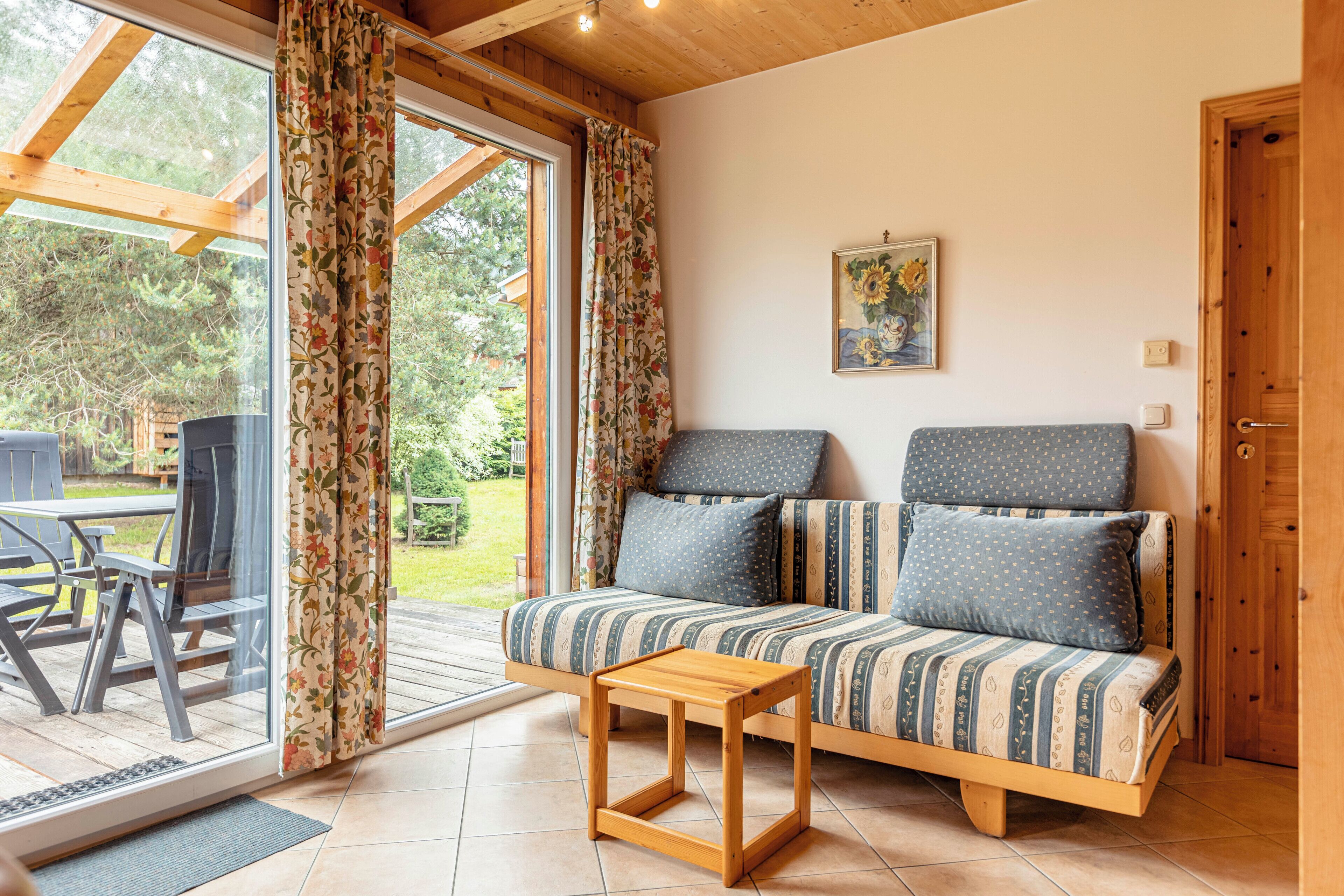 A cozy room with a sofa, a small wooden table, and a view of the outdoors.