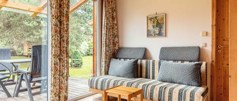A cozy room with a sofa, a small wooden table, and a view of the outdoors.