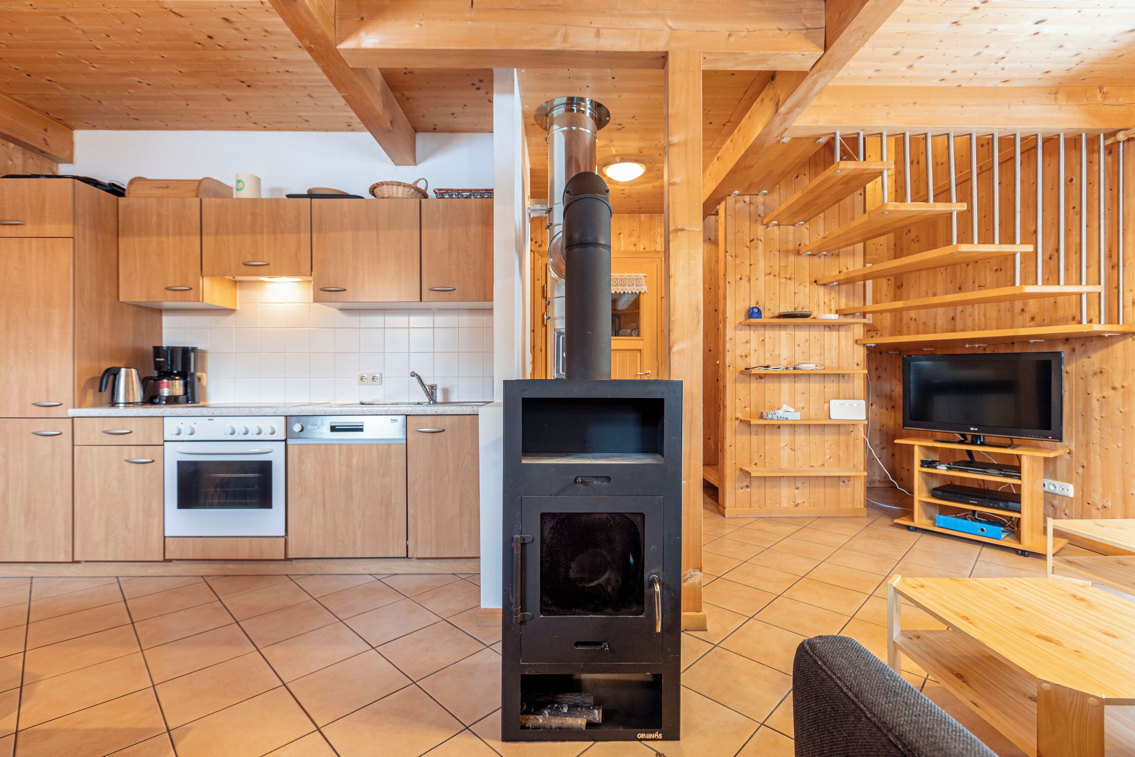 A modern kitchen with wooden cabinets, a stove, and a dining area with a table and chairs.