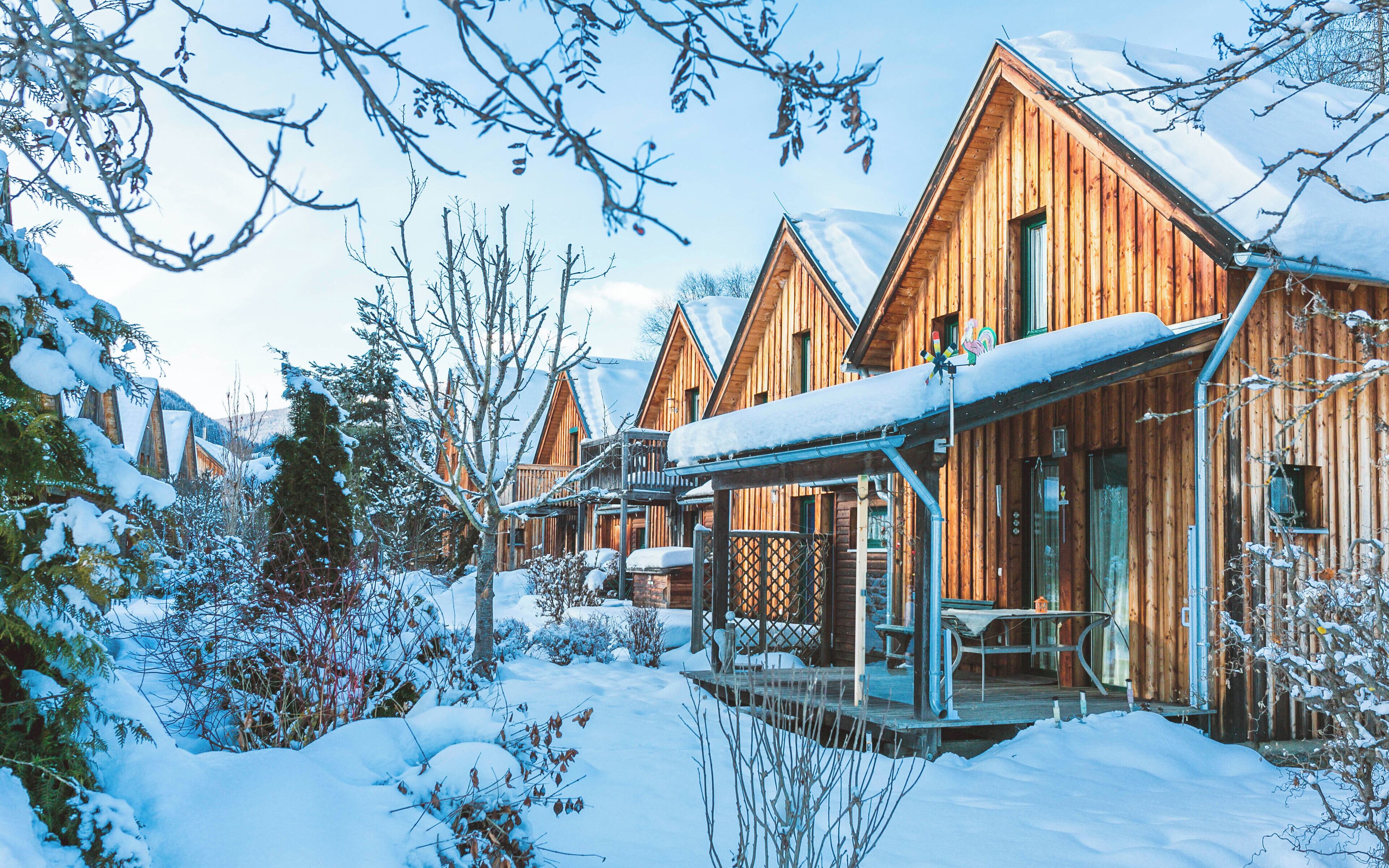 A wooden cabin with a covered porch and snow-covered surroundings.