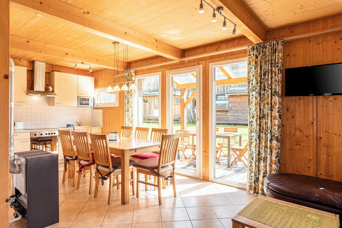 A wooden interior with a kitchen, dining area, and a TV mounted on the wall.