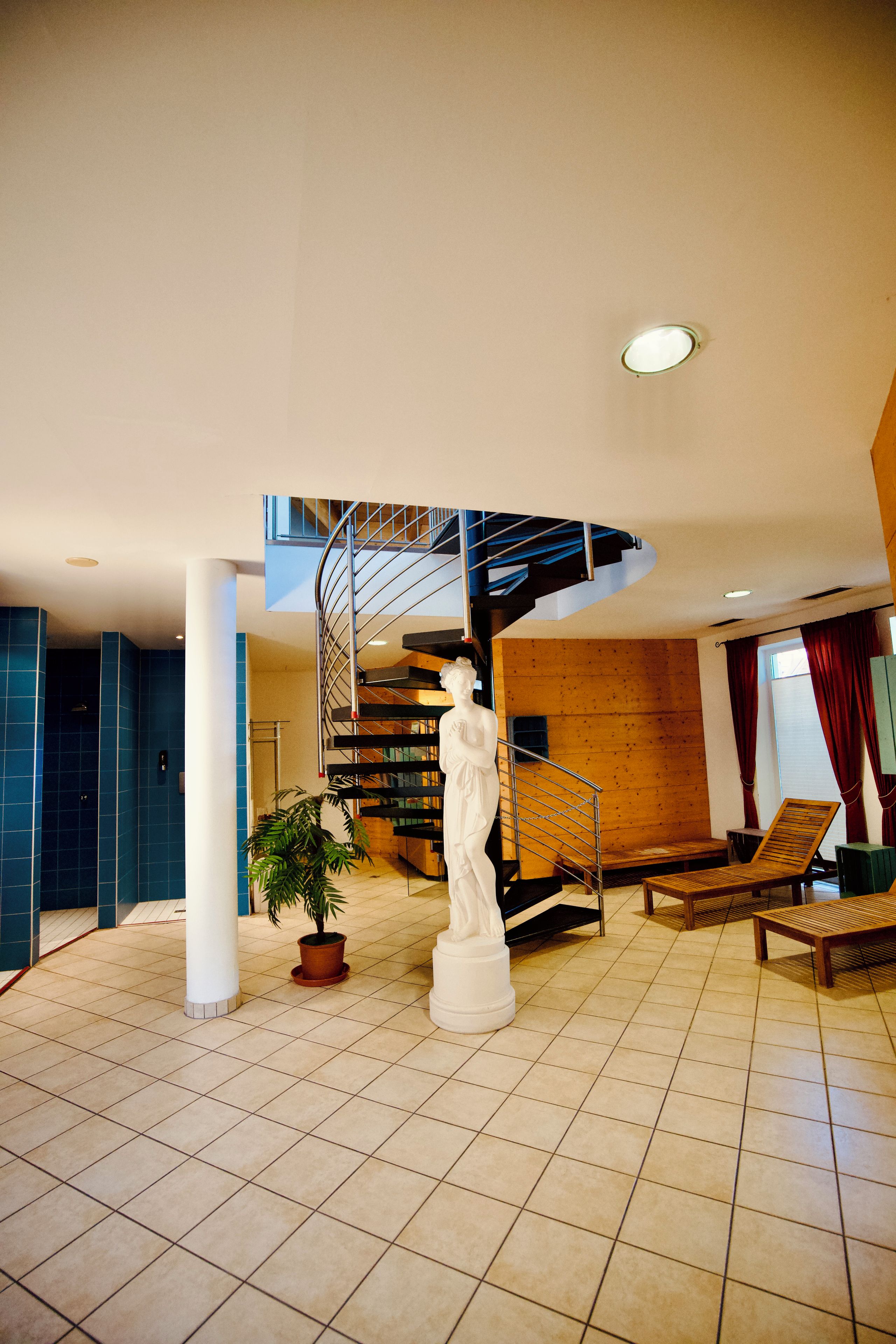 A spacious lobby with a modern staircase, a white statue, and a seating area.