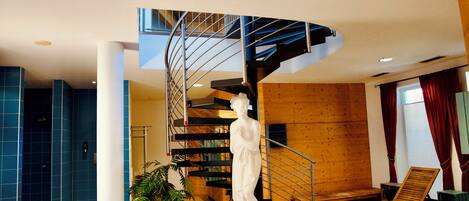 A spacious lobby with a modern staircase, a white statue, and a seating area.