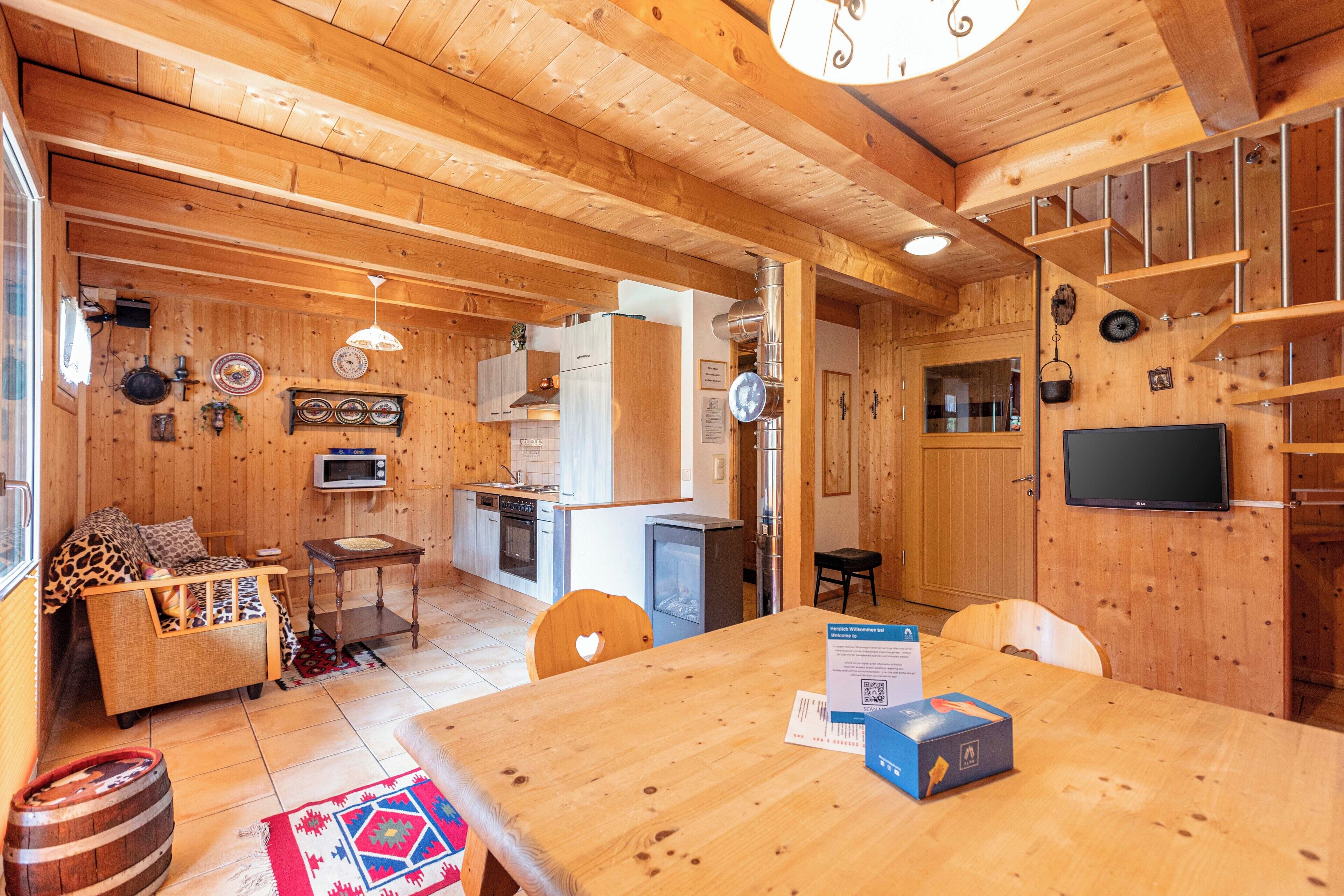 Ein Holzinterieur mit Esstisch, Stühlen, einer Couch und einer Küchenzeile.