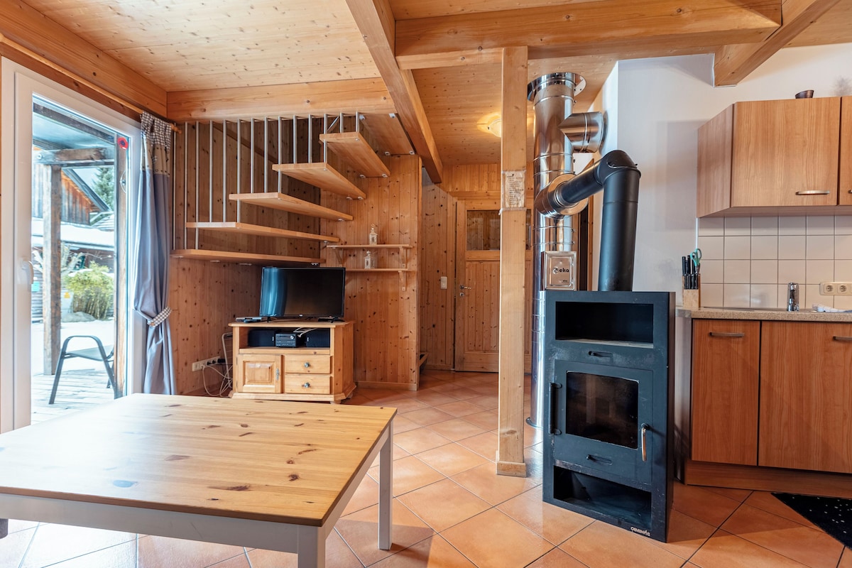 A wooden interior with a kitchen area, including a stove, cabinets, and a dining table.