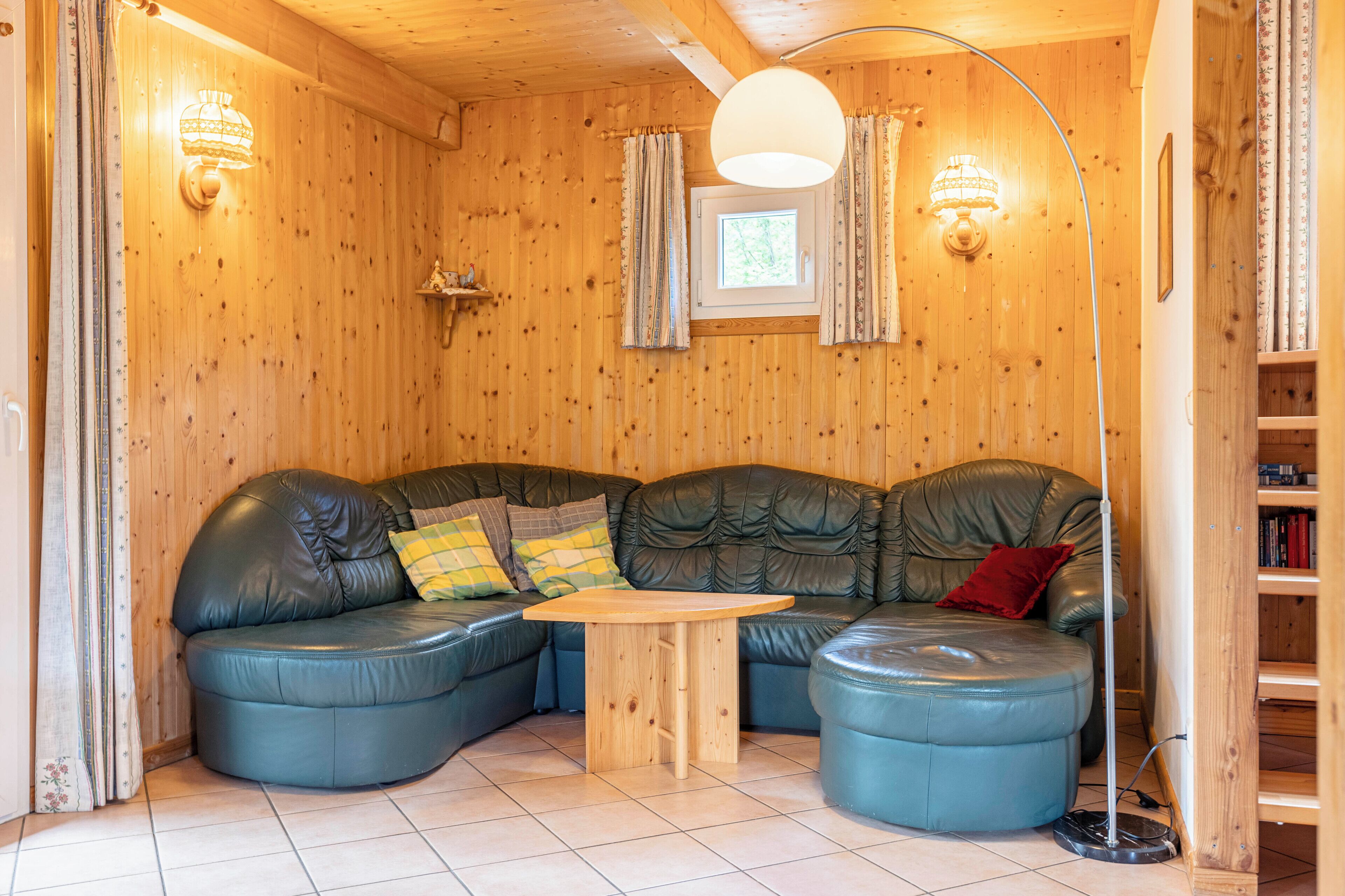 A cozy room with a curved leather sofa, a small wooden table, and a floor lamp.