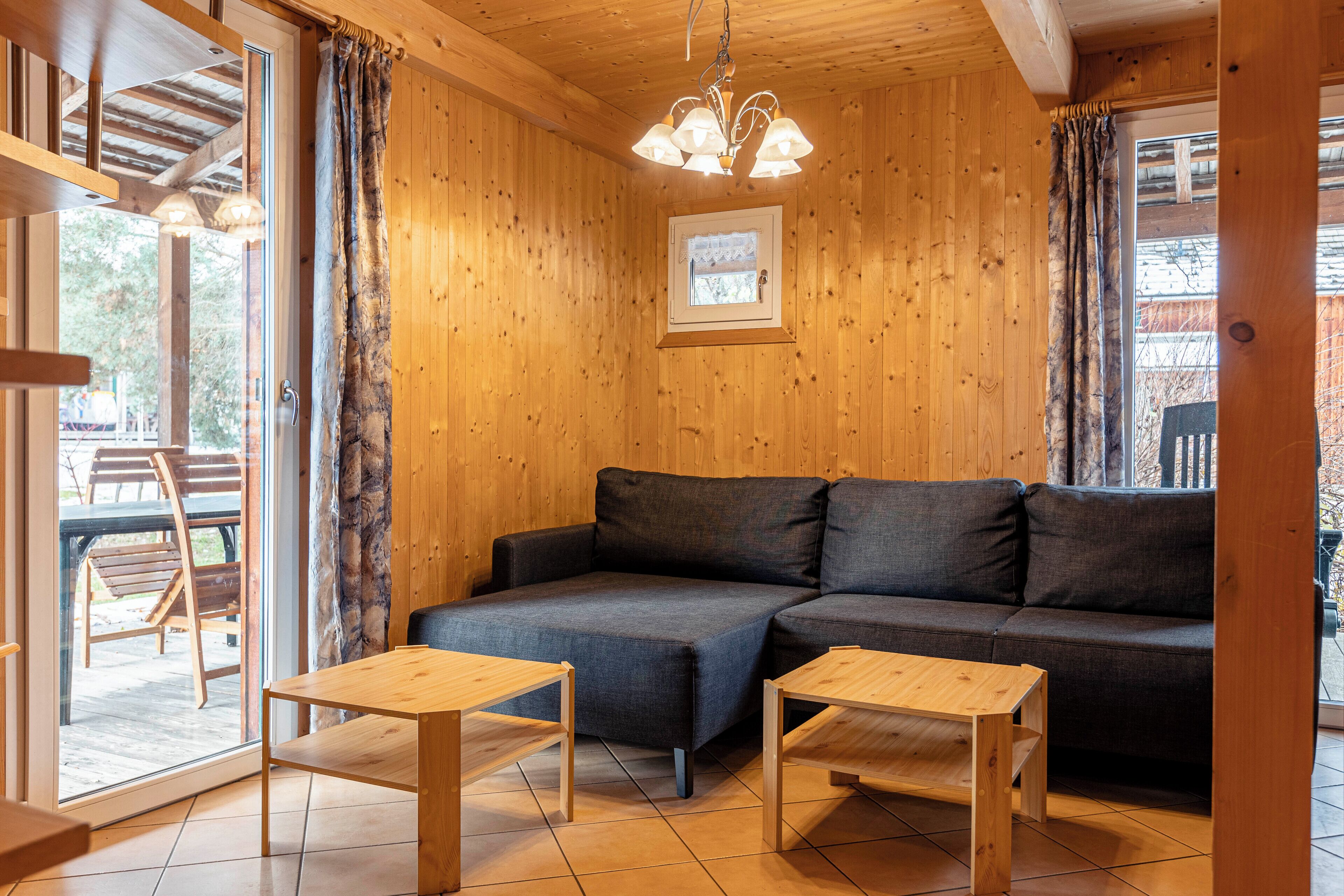 A wooden interior with a sofa, two wooden tables, and a ceiling light fixture.