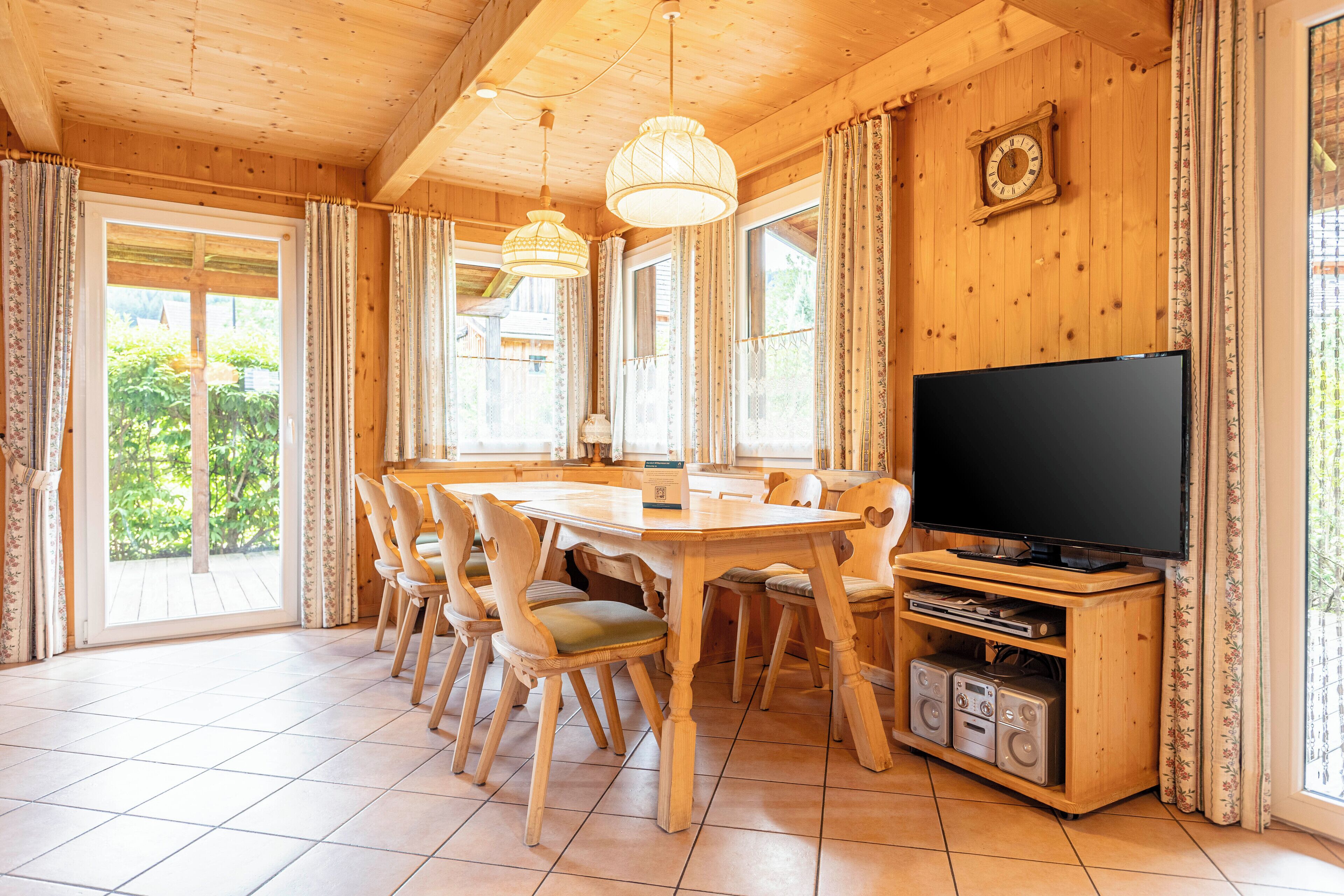 Un intérieur en bois comprenant une table à manger, des chaises, un téléviseur et une horloge murale.