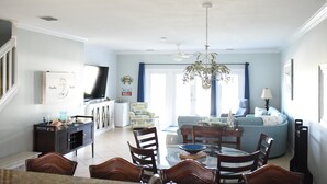 Zona pranzo con un lampadario, una televisione e un divano sullo sfondo.