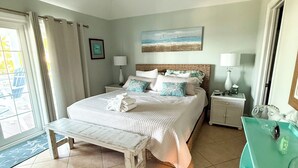 Una camera da letto con un letto, comodini, una panca, una cassettiera e un quadro appeso al muro.