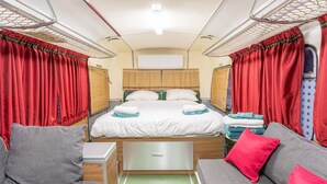 Un intérieur compact et bien éclairé, comprenant un lit, deux canapés et une petite table.