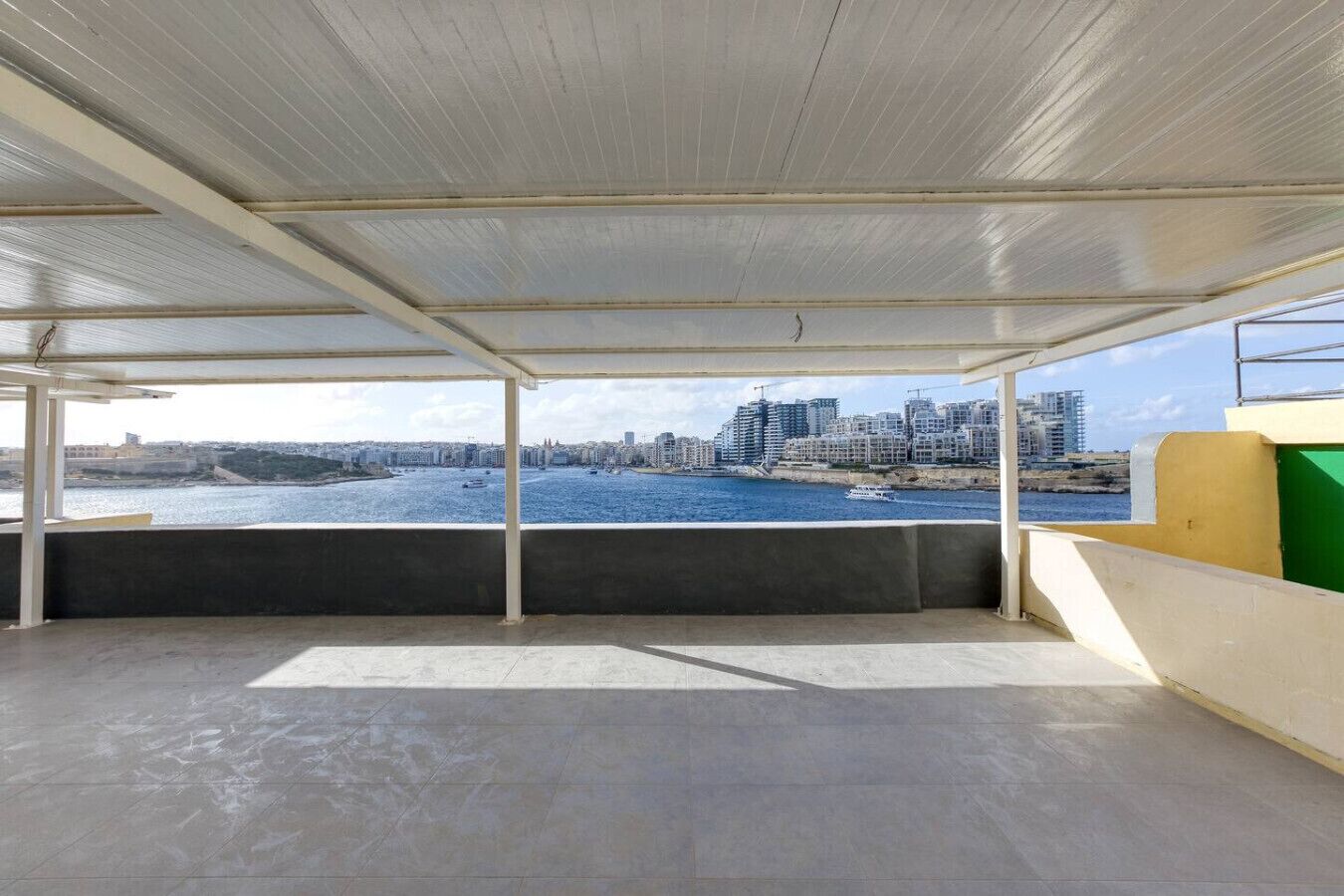 En rummelig balkon med krystalklart hav og byudsigt.