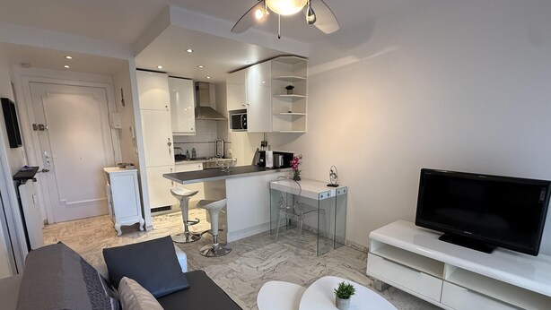 A modern living room with a sofa, a TV, and a small coffee table. - Central Studio in Cannes Near The Martinez- 2351 (Cannes)