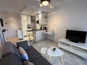Una sala de estar moderna con un sofá, un televisor y una pequeña mesa de centro.