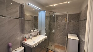 A modern bathroom with a glass-enclosed shower, a vanity with a mirror, and a toilet. - Central Studio in Cannes Near The Martinez- 2351 (Cannes)