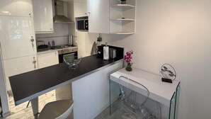 A modern kitchen with white cabinetry, a black countertop, and a glass chair. - Central Studio in Cannes Near The Martinez- 2351 (Cannes)