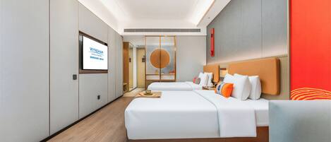 A modern hotel room with a large bed, a sofa, and a TV displaying 'Wyndham Hotels & Resorts'.