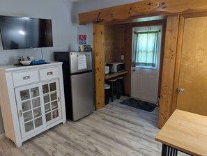 Eine kleine Küche mit Kühlschrank, Mikrowelle und einer Essecke.