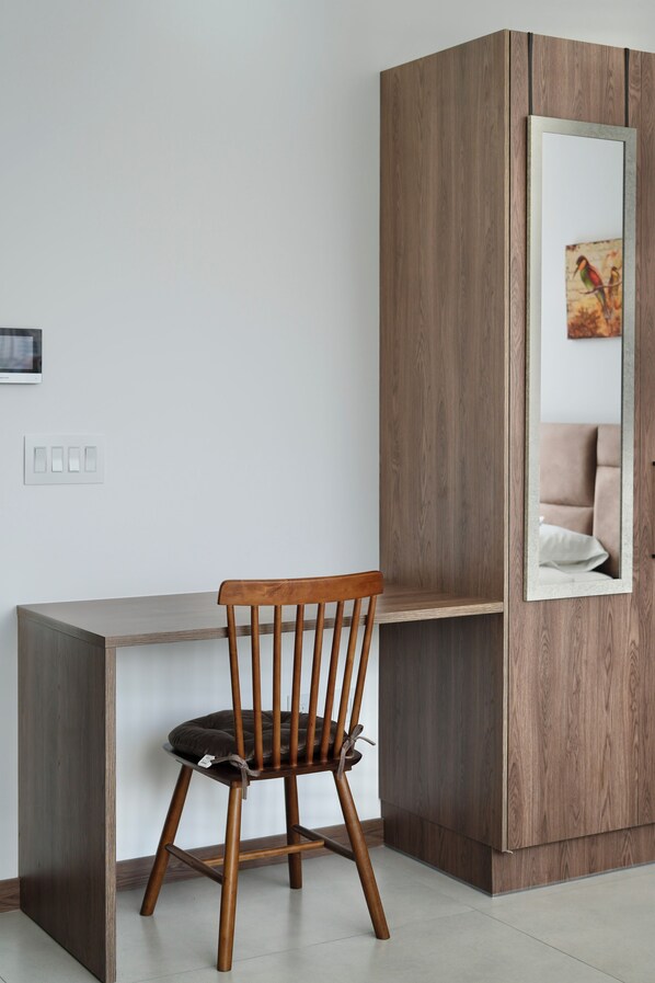 A modern room with a wooden chair, a built-in desk, and a wardrobe with a mirror. - Seis Residences (Quito)