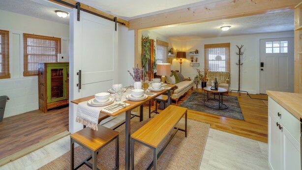 Un comedor con una mesa de madera dispuesta para cuatro, un armario verde y una cocina con encimera de madera.