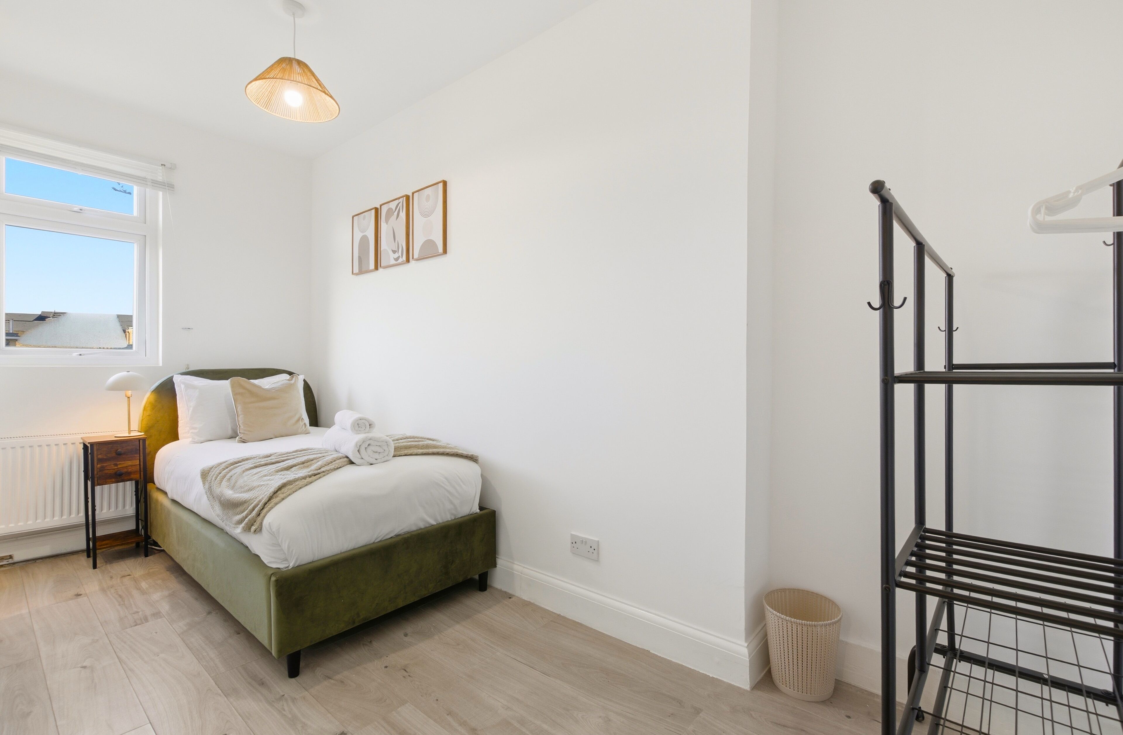 A bedroom with a bed, bedside table, lamp, and a window.
