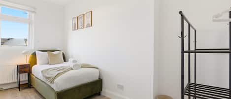 A bedroom with a bed, bedside table, lamp, and a window.