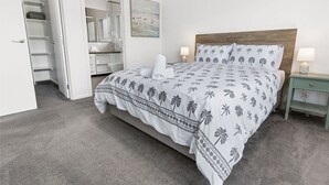 A bedroom with a bed, bedside tables, a wardrobe, and a bathroom visible through an open door.