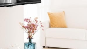 A modern living room with a white sofa, a blue vase with flowers, and a tray with white cups and saucers. - Dimora Margherita (Caserta)