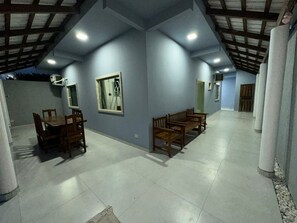 A spacious room with a high ceiling and a dining area with wooden furniture. - BEACH HOUSE (Prado)